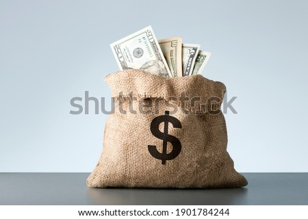 Burlap with dollar banknotes on gray background. Bribe or bonus concept.
