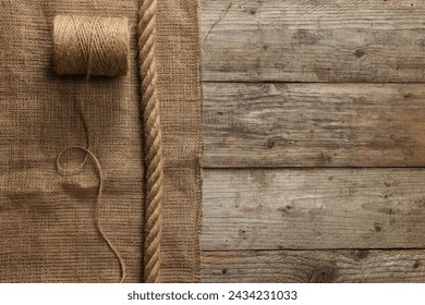 Burlap fabric, spool of thread and jute on wooden table, top view. Space for text