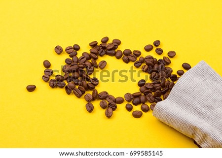 Burlap sack full of coffee beans on yellow background