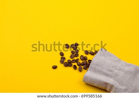 Burlap sack full of coffee beans on yellow background
