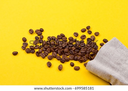 Burlap sack full of coffee beans on yellow background