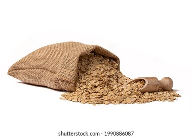 A burlap sack lies on a white background. Oatmeal in the bag. Nearby lies a wooden scoop. - Shutterstock ID 1990886087