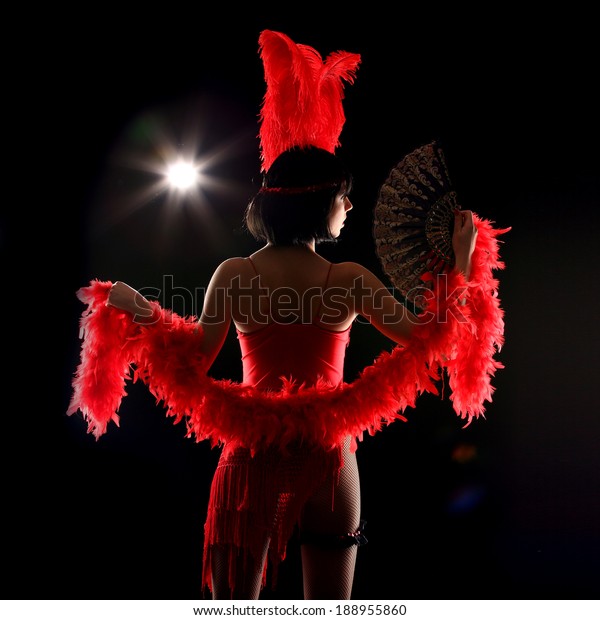 Burlesque dancer with red
plumage and red short dress, black and red background, on the
stage