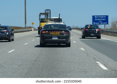 Burlington Ontario Canada May 7 2022: Close view of OPP Dodge Charger police cruiser interceptor following a car on the highway. Dangerous, careless driving, speeding, DUI, traffic violations concept.