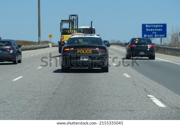 Burlington Ontario Canada May 7 2022: Close view\
of OPP Dodge Charger police cruiser interceptor following a car on\
the highway. Dangerous, careless driving, speeding, DUI, traffic\
violations concept.