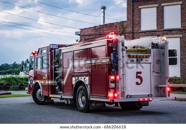 Burlington, Vermont, USA - July 19 2017: Red fire\
truck number 5 with lights on in front of a house in Burlington,\
Vermont, USA.