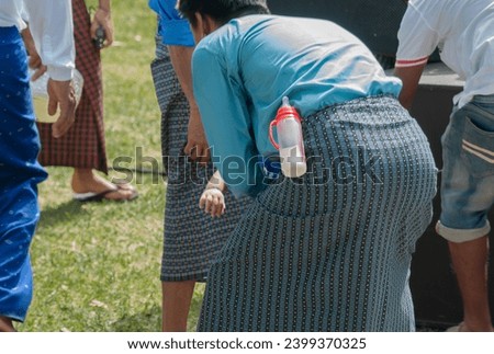 Burmese man carries a baby bottle to participate in the Kathina merit-making festival on the end of Buddhist Lent for Burmese brothers and sisters in Thailand.