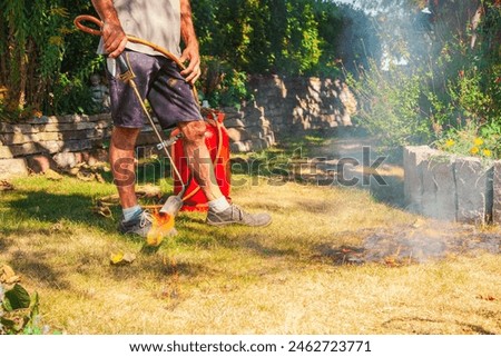 Image, Stock Photo Burning lawn. Man destroying dry dead grass with weed burner, garden gas burner. Fire spreads quickly through dry grass in garden, close up. Forest fire danger