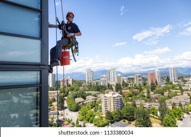 Burnaby, Vancouver, British Columbia, Canada - July 06, 2018: High rise rope access window cleaner is working during a hot sunny summer day.