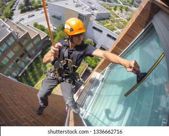 Burnaby, Vancouver, British Columbia, Canada - July 2, 2018: High rise rope access window cleaner is working during a summer day.