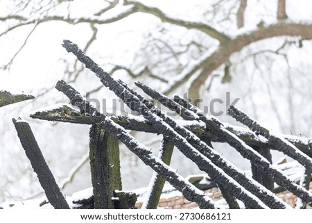 Burned down barn covered in snow after a blizzard snowstorm with the black wood and construction carcas contrasting against the white winter landscape