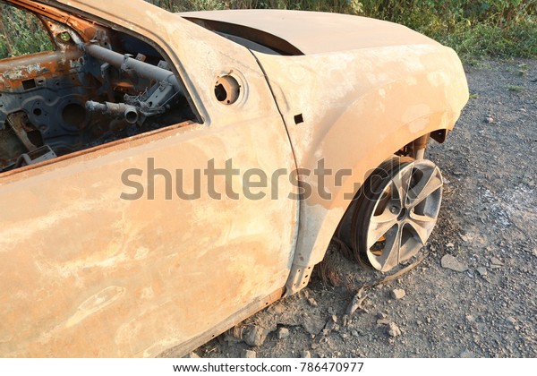 Burned to the ground car wreck on the side of the road,\
grunge 