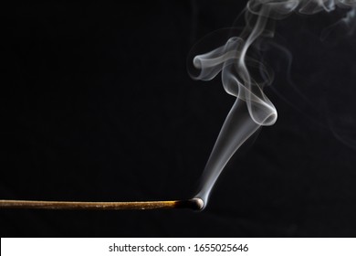 a burned match still smoking against a black background 