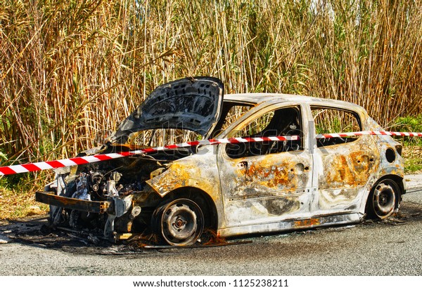 Burned\
out stolen car abandoned at the side of the\
road