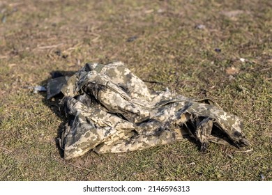 Burned And Torn Piece Of Ukrainian Army Soldier's Pixel Camouflage Military Uniform Who Died In The Village During Battle In Tank. War Of Russia Against Ukraine. Concept Of Invasion And Genocide. 