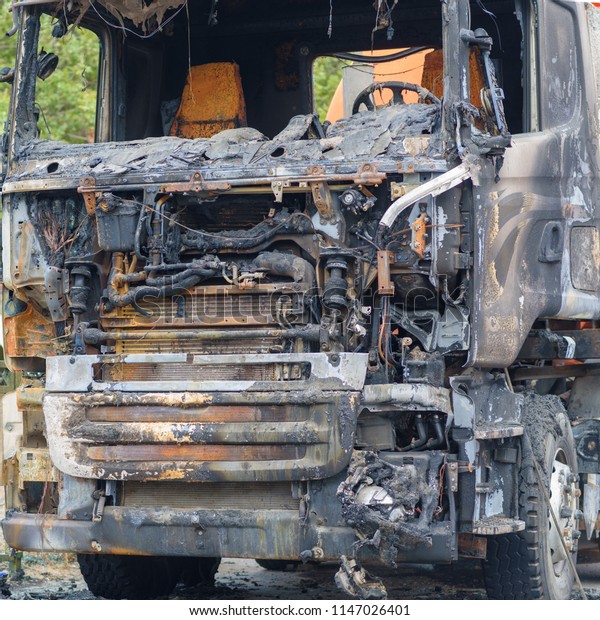 Burned truck in a roadside\
with a burnt-out\
driver\'s cab,  accident.