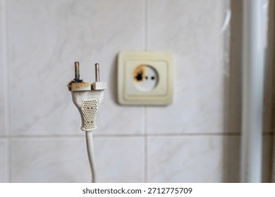 Burned wall socket and damaged plug showing clear signs of overheating and electrical malfunction, useful for illustrating safety warnings and home fire-prevention topics.