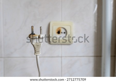 Burned wall socket and damaged plug showing clear signs of overheating and electrical malfunction, useful for illustrating safety warnings and home fire-prevention topics.