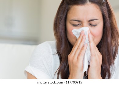 Burnette woman blowing nose into tissue