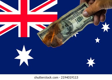 A Burning $100 Bill On The Background Of The Flag Of Australia. The Concept Of The Financial Crisis And High Inflation. The Trend Of Abandoning The Dollar.