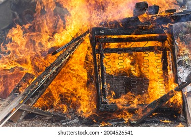 Burning Barricade, Large Armchair Burning On Bonfire, Alight And Very Hot, Polluting Disposal Of Rubbish Not Environmentally Friendly, Chair Springs Visible And Wood.