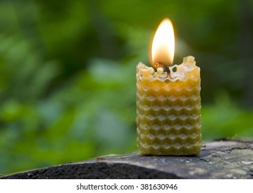 Burning Beeswax Candle On An Old Log