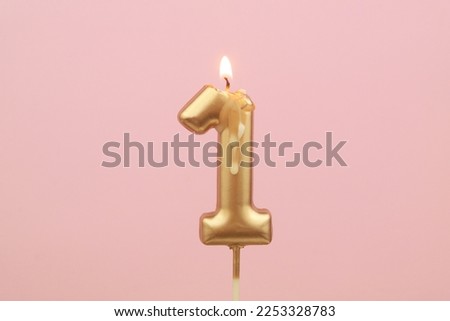 Burning birthday candles on pink background, number 1