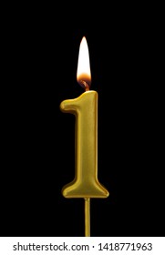 Burning birthday golden candle isolated on black background, number 1