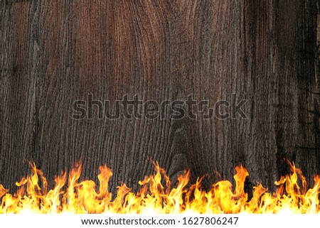 Burning black board with open red fire flame border, copy space, text place. Black burned wooden board texture. Burnt wooden Board. Burned scratched hardwood surface. Smoking wood plank bbq