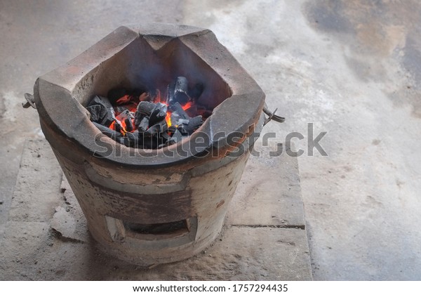 Burning black charcoal in old charcoal stove clay earthenware for cooking with copy space close-up.