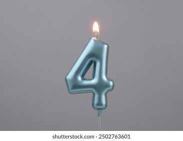 Burning blue birthday candle on gray background, number 4