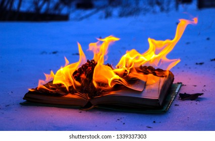 burning book in the snow. pages with the text in the open book burn with a bright flame.