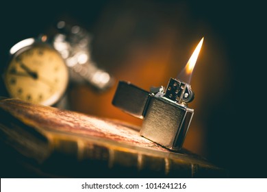 Burning brushed chrome lighter with windproof on the wooden desk. One of everyday carry item for men. 