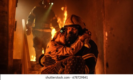 Burning Building. Group Of Firemen Descend on Burning Stairs. On foreground one Fireman Holds Saved Girl in His Arms.