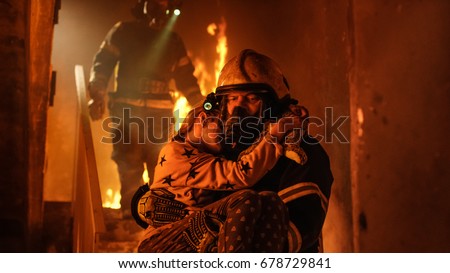 Burning Building. Group Of Firemen Descend on Burning Stairs. On foreground one Fireman Holds Saved Girl in His Arms.