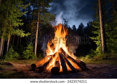 Burning campfire on a dark night in a forest. The bonfire burns in the forest. camp fire in the autumn during vacation in the mountains. Beautiful landscape of nature and trees. Sparks and flames.
