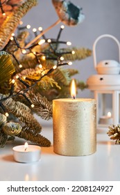 A burning candle against the backdrop of a Christmas decoration with garlands of lights. Happy New Year and Merry Christmas