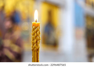 A burning candle against a background of blurred icons in an Orthodox church. The concept of Orthodoxy. Soft light, selective focus.