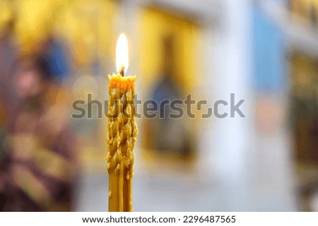 A burning candle against a background of blurred icons in an Orthodox church. The concept of Orthodoxy. Soft light, selective focus.