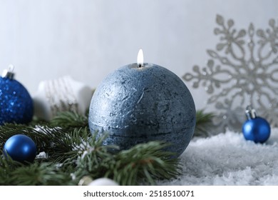 Burning candle, baubles and fir branches on artificial snow, closeup. Christmas atmosphere - Powered by Shutterstock