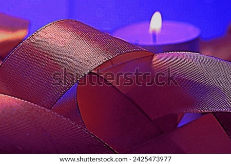 A burning candle, a beautiful, shiny, silk ribbon.