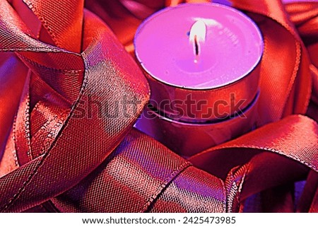 A burning candle, a beautiful, shiny, silk ribbon.