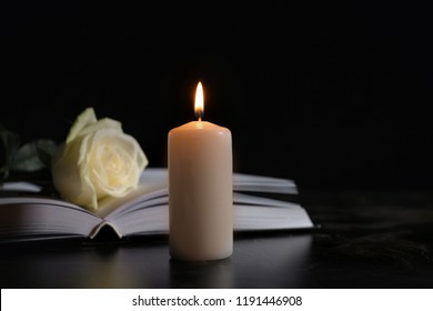 Burning candle, book and white rose on table in darkness, space for text. Funeral symbol - Shutterstock ID 1191446908