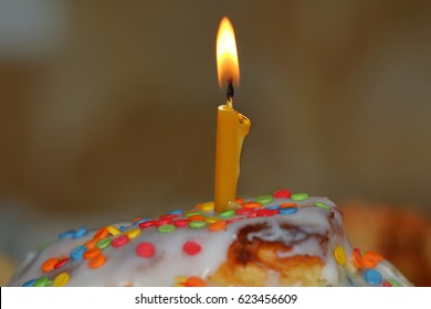 A burning candle in the Easter cake close up