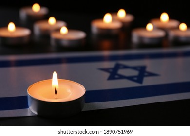 Burning Candle And Flag Of Israel On Black Table. Holocaust Memory Day