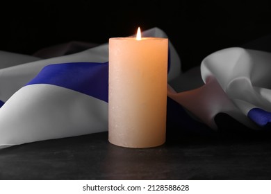Burning candle and flag of Israel on dark background. Holocaust remembrance day