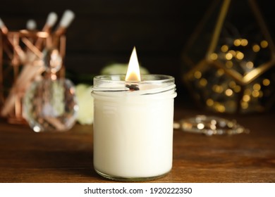 Burning Candle And Jewelry On Wooden Table