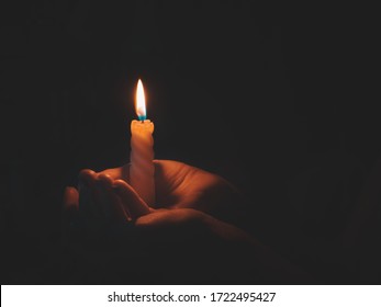 Burning candle in male hand on a black background. 