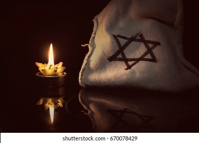 A burning candle next to the star of David on a black background. A symbol of remembrance of the victims of the genocide of the Jew in the third Reich in Germany.