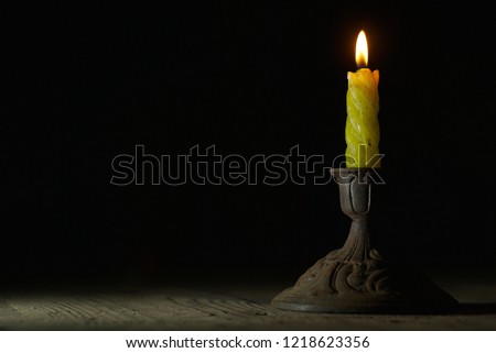  Burning candle on a antique candlestick in the dark                              
